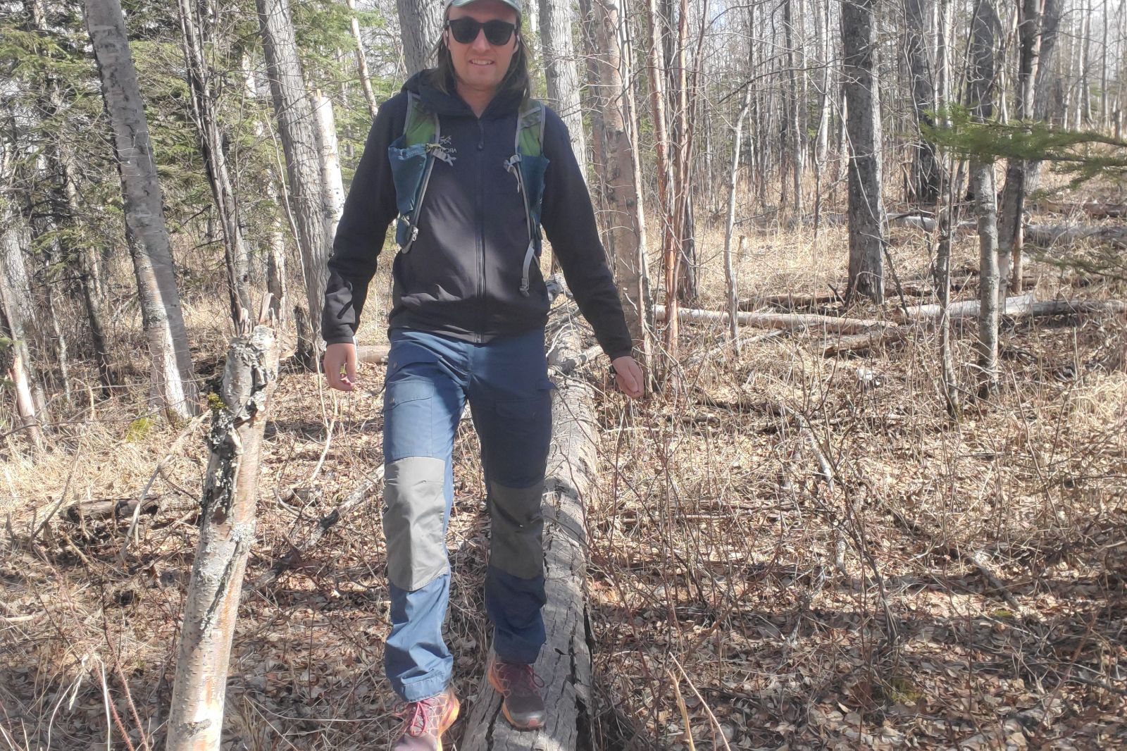 A man walk along a fallen log.