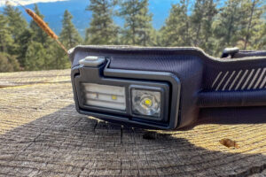 a closeup of a headlamp sitting on a stump in a forest.