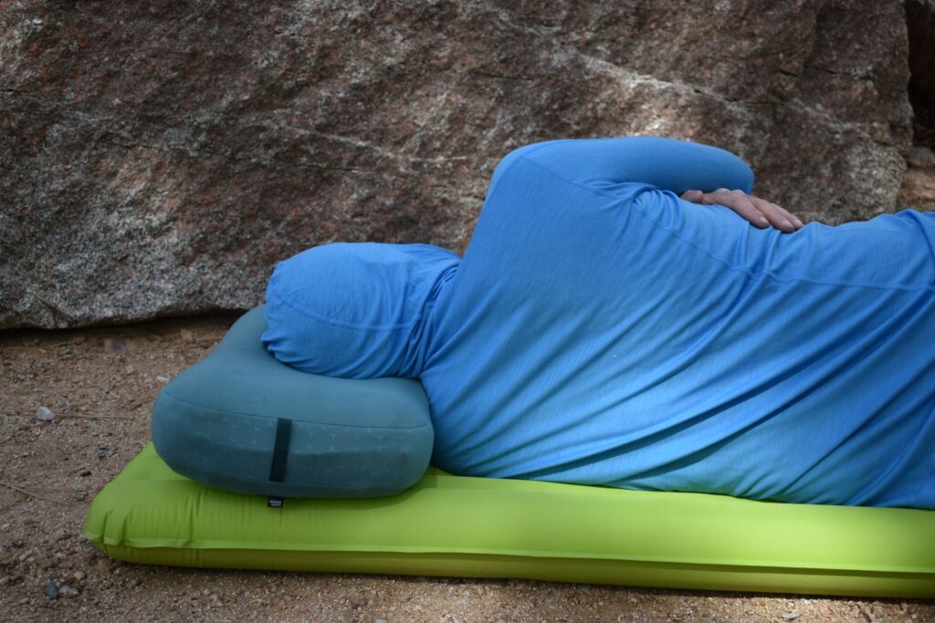 a hiker sleeps on his side with his neck supported by a camping pillow