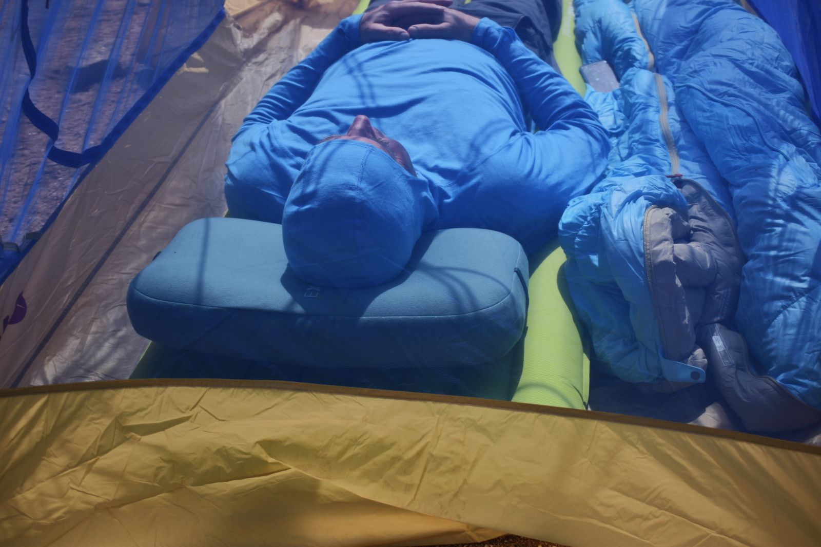 looking through a tent's mesh at a camper resting on the Exped Mega Pillow and Exped sleeping pad