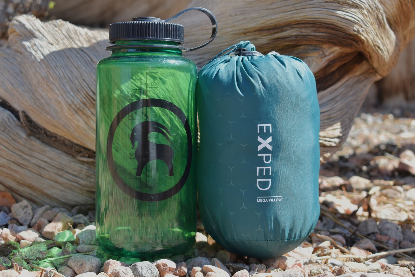 A Nalgene bottle and packed camp pillow sit by side for a size comparison