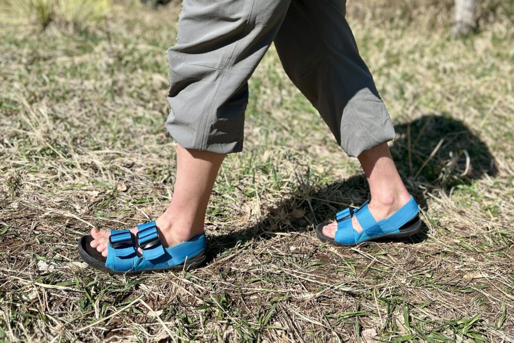 Close up image from the thighs down of a person walking in a grassy setting.