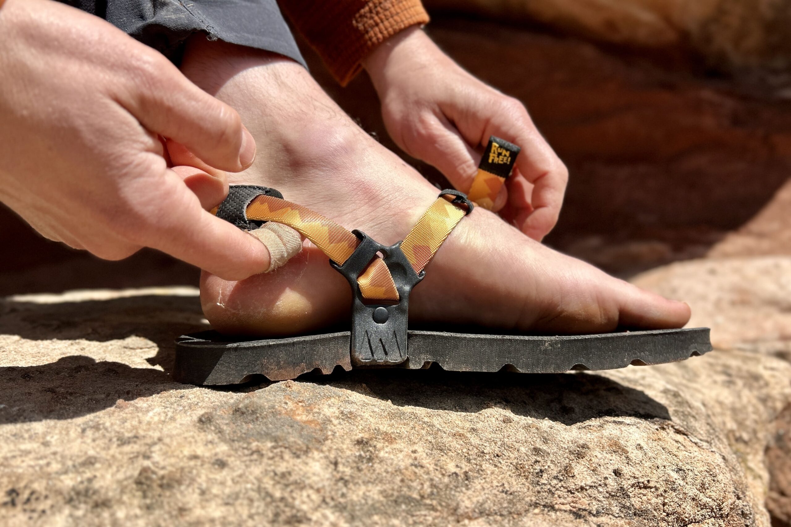 Close up image of a person tightening a sandal on one foot
