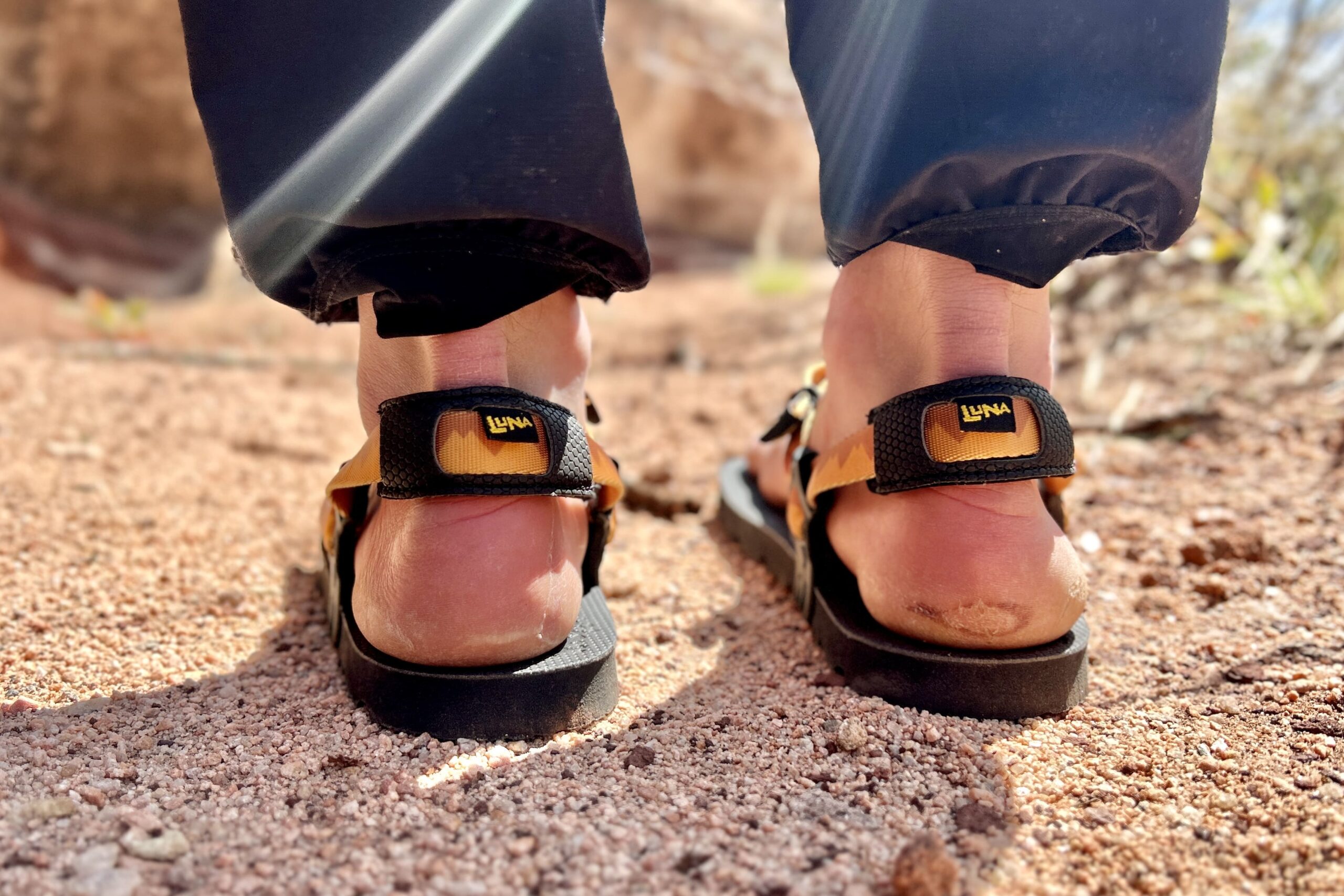 Close up image of two feet from behind in a pair of sandals