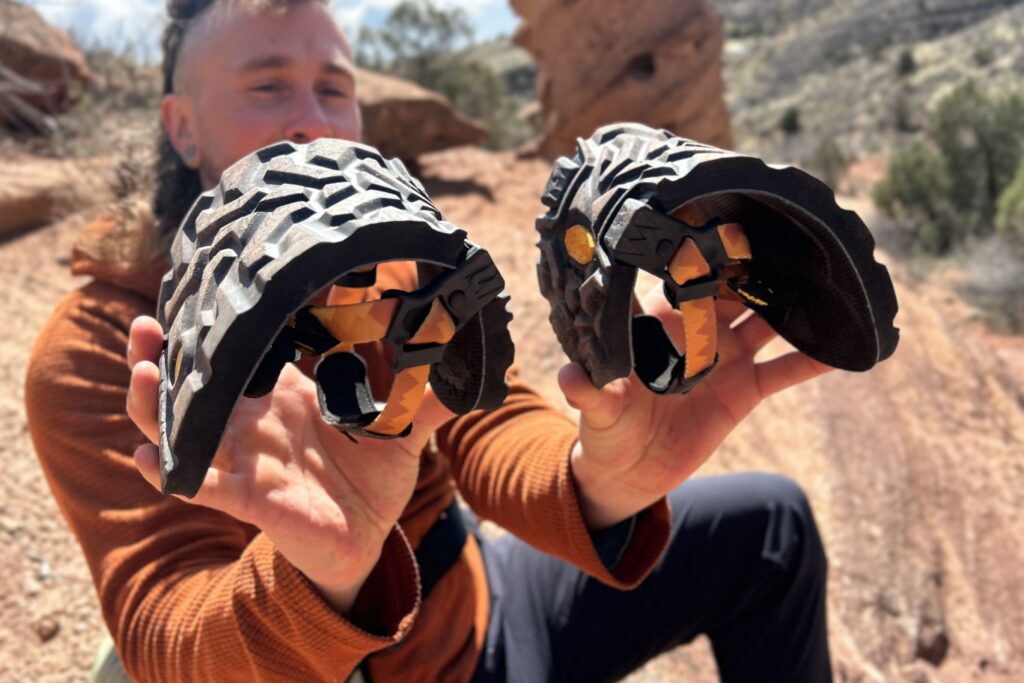 Close up image of a person holding out two hiking sandals folded into arches