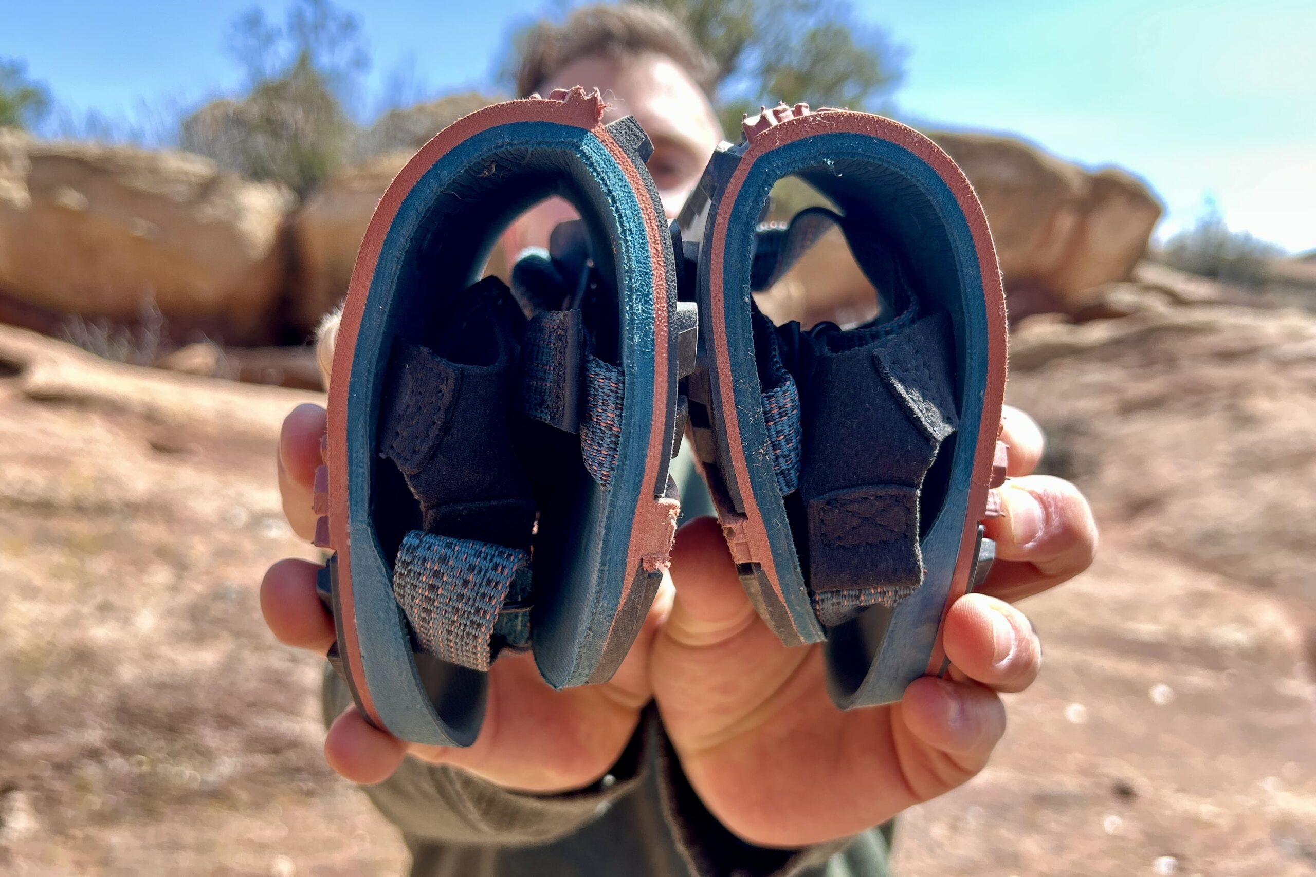 Close up image of a person holding out two hiking sandals folded in half