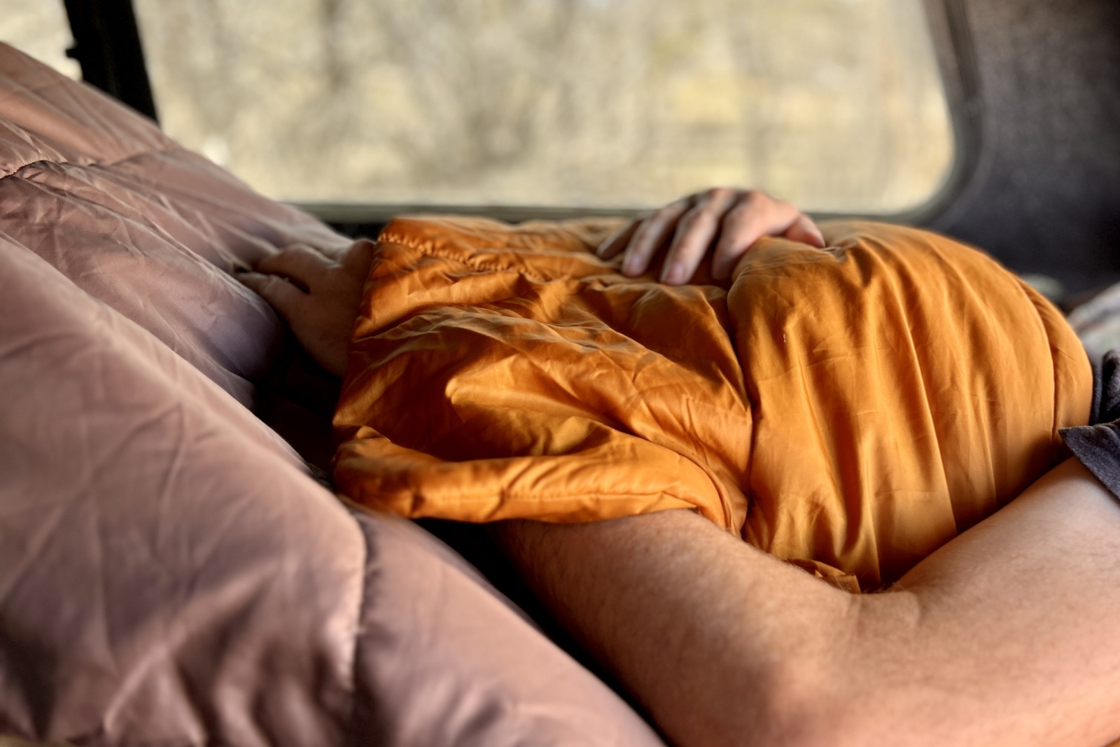 Close up image of the blanketfold of a sleeping bag and a person's hands resting on top.