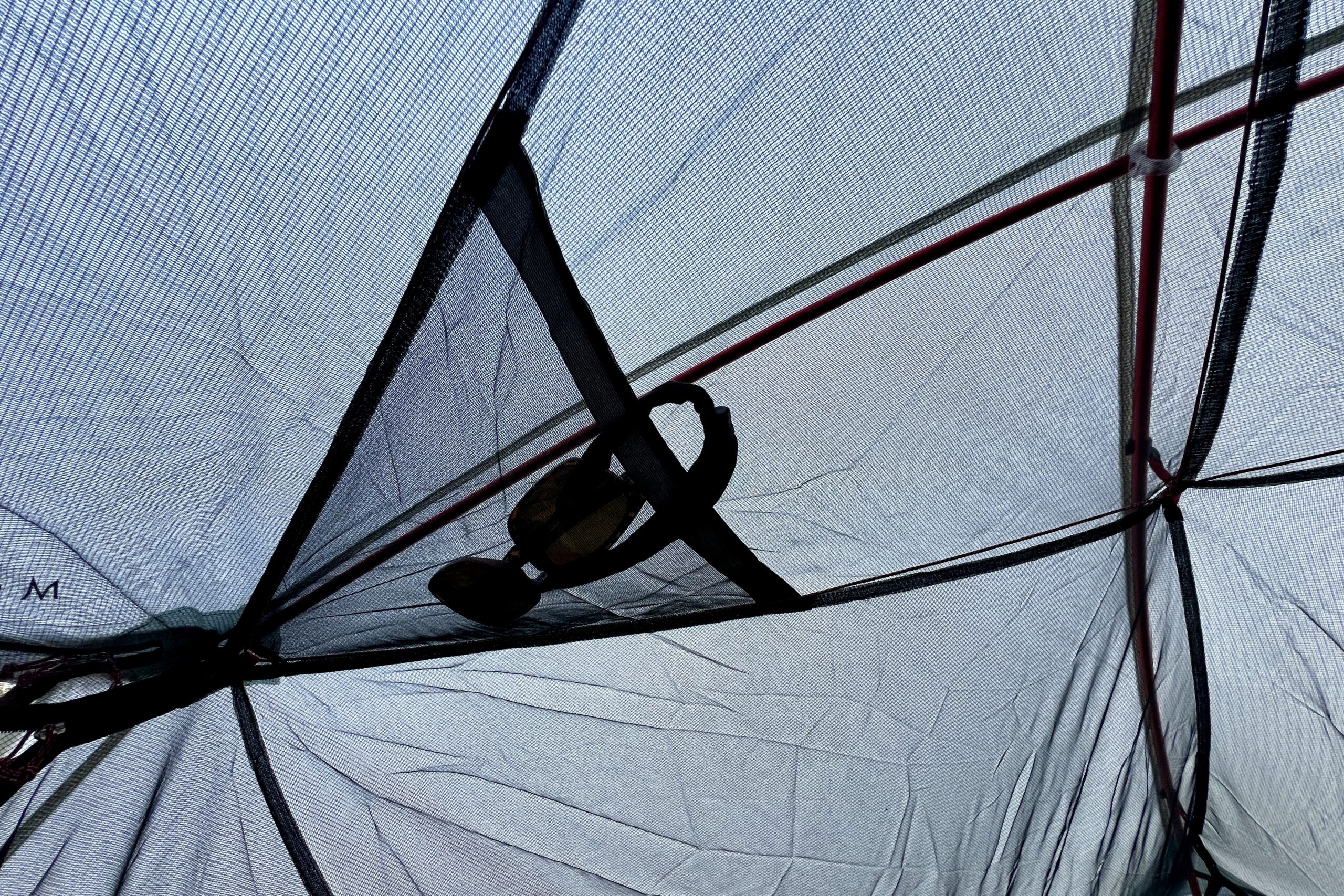 sunglasses stuffed in a mesh pocket of a tent ceiling