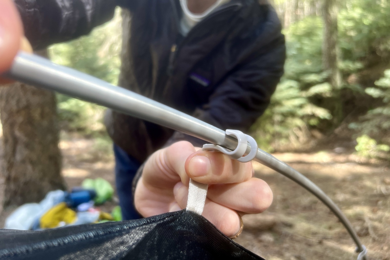 a close up of a hiker attached tent poles to the hooks on the tent body