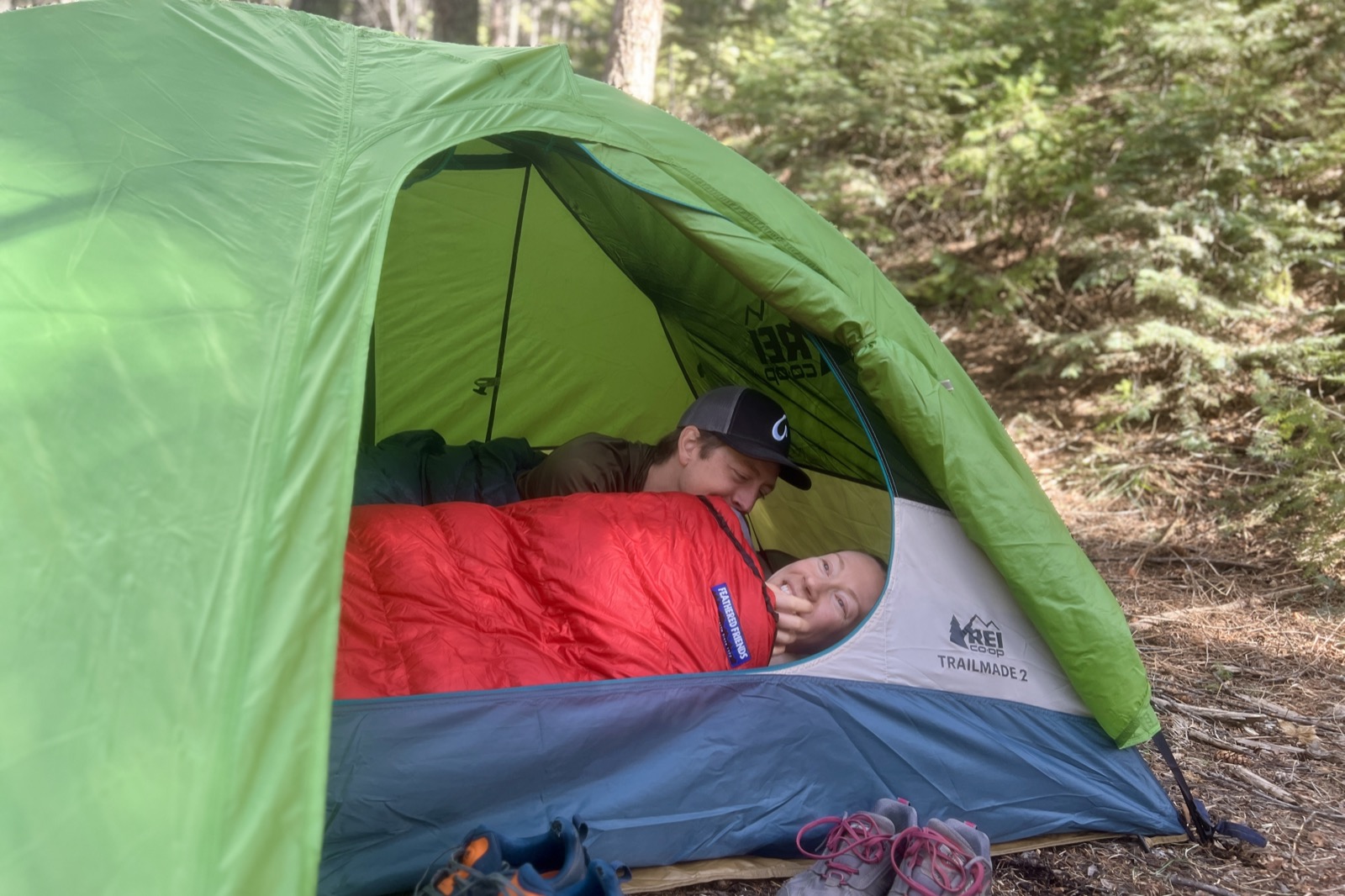 two hikers lay down in a green tent
