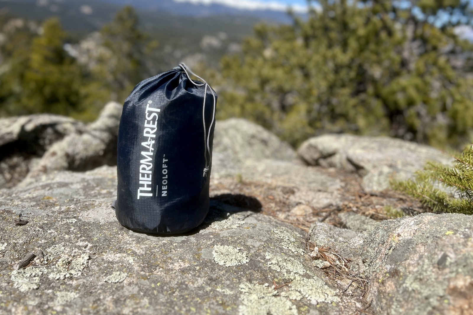 a sleeping pad in a stuff sack sitting on a rock