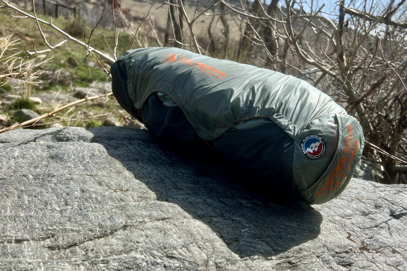 a tent sits packed up in its stuff sack on a rock