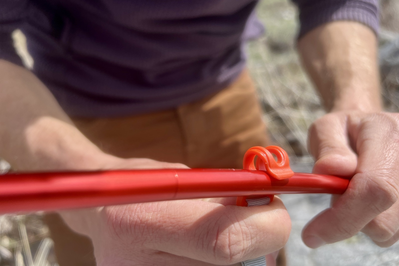 a close up of a hiker clipping a tent to its poles