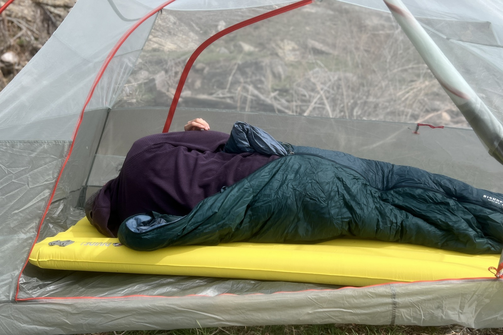 a hiker sleeps on his side on a yellow sleeping pad in a tent