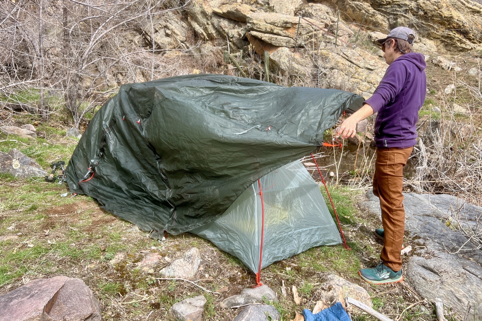 a hiker pulls the rain fly onto a tent