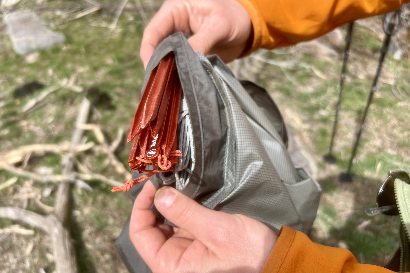 a close up of hands showing stakes in a secret pocket in a tent stuff sack