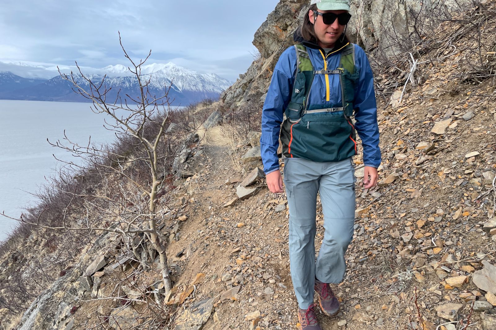 A man walks along a narrow trail above the ocean.