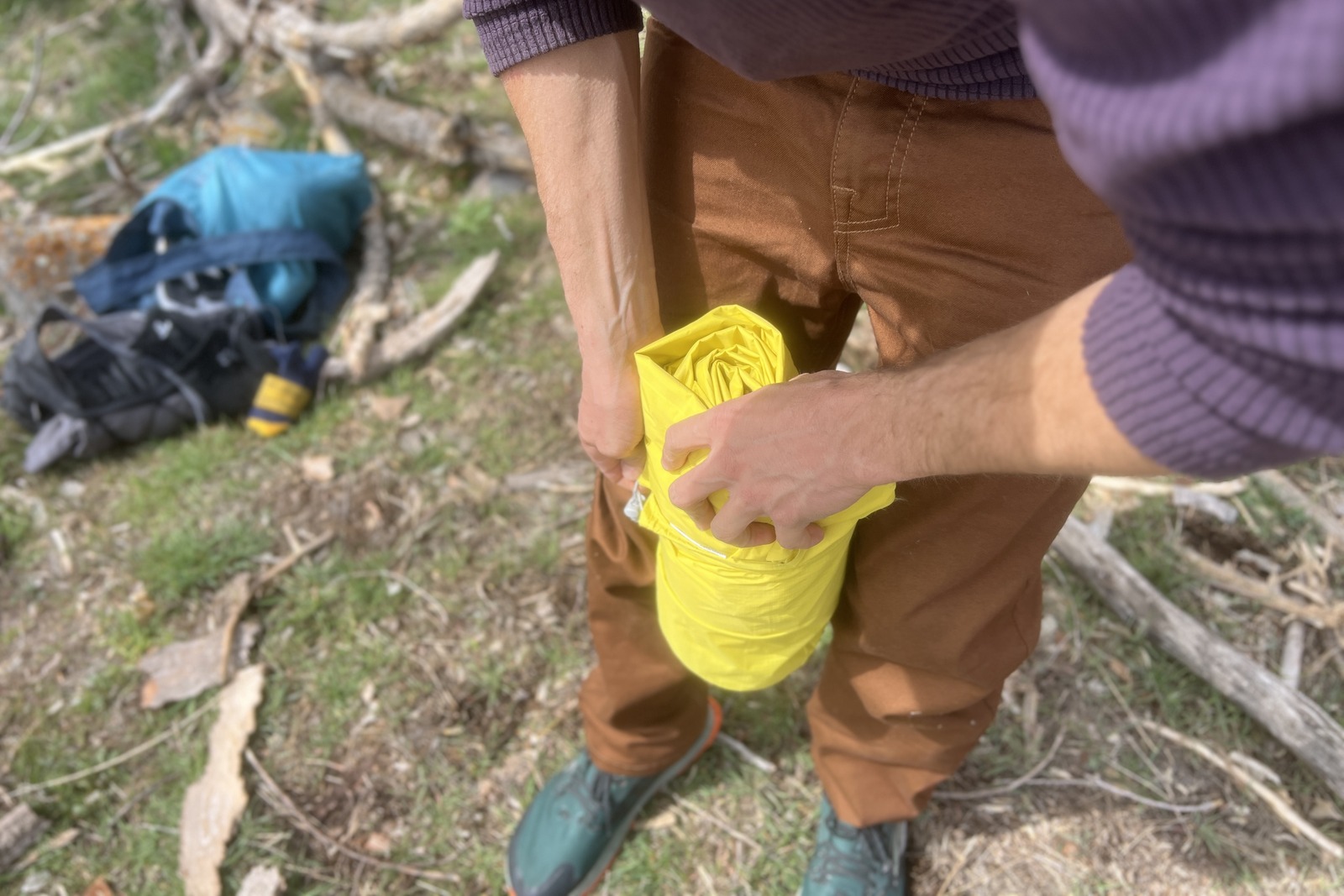 a hiker stuffs a yellow sleeping pad into a stuff sack