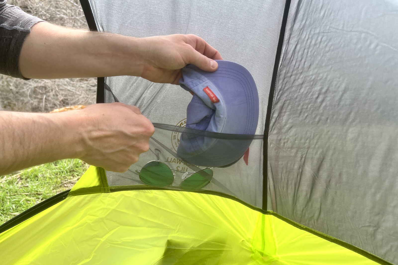 a hiker stuffs a hat into a tent's interior mesh pocket