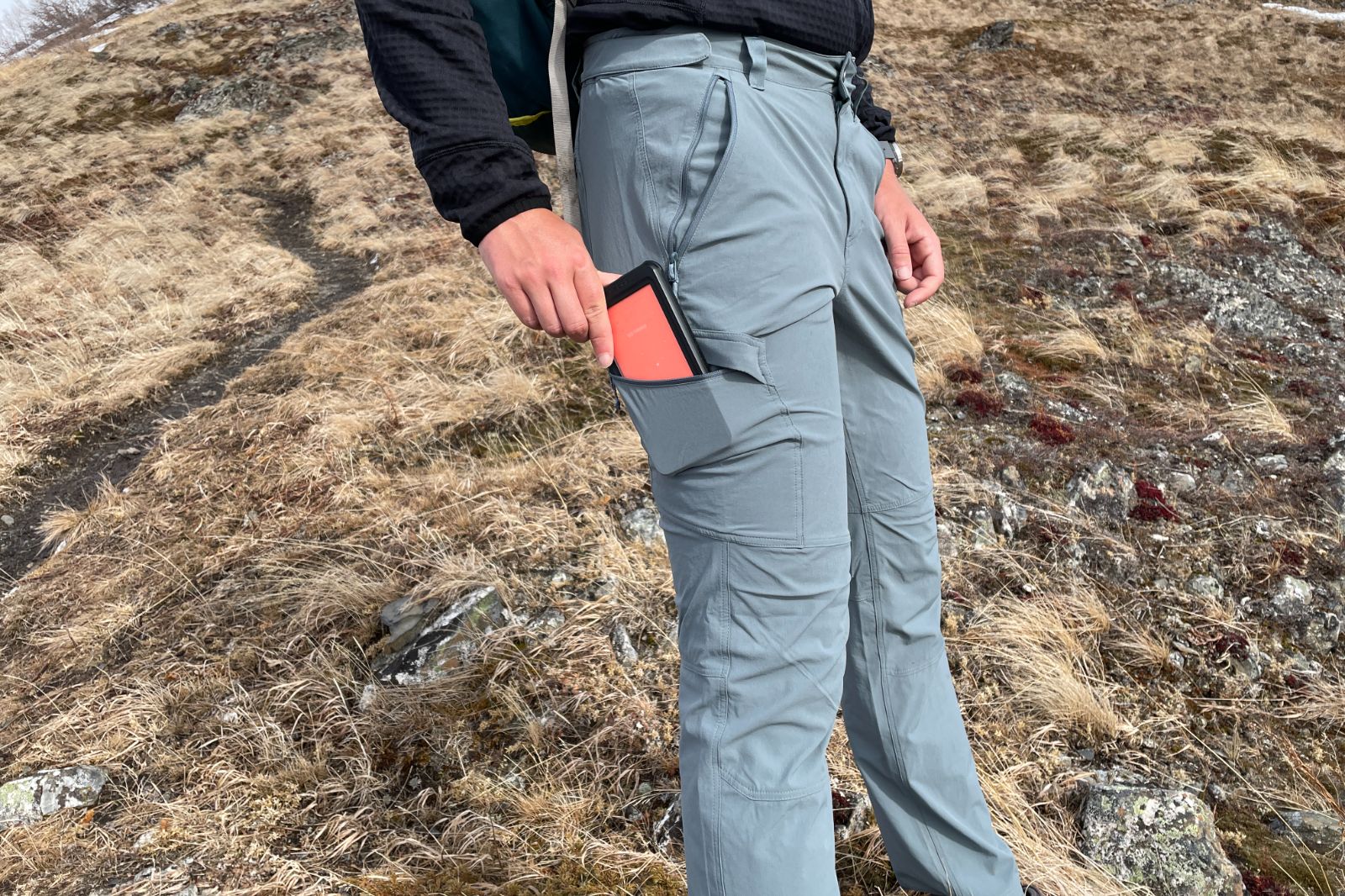A man puts a cell phone in the side pocket of his pants.