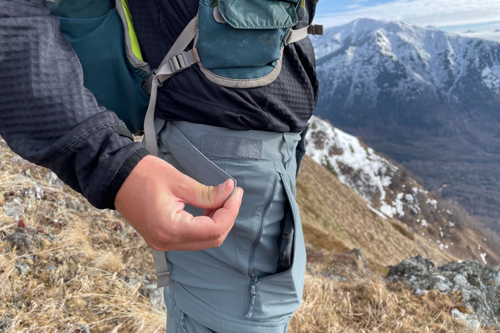 A closeup of the waist adjustment system on a pair of hiking pants.