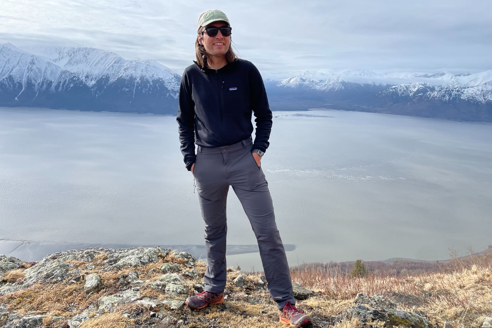 A man stands with a mountain and ocean view.
