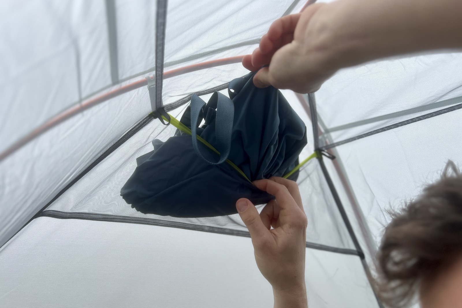 a close up of a hiker pulling gear out out of a mesh pocket in a tent