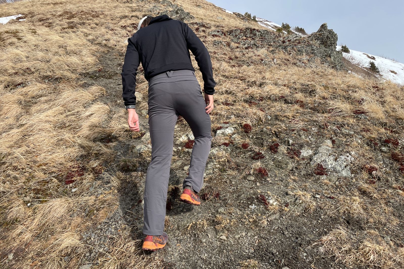A man hikes up a steep hillside.