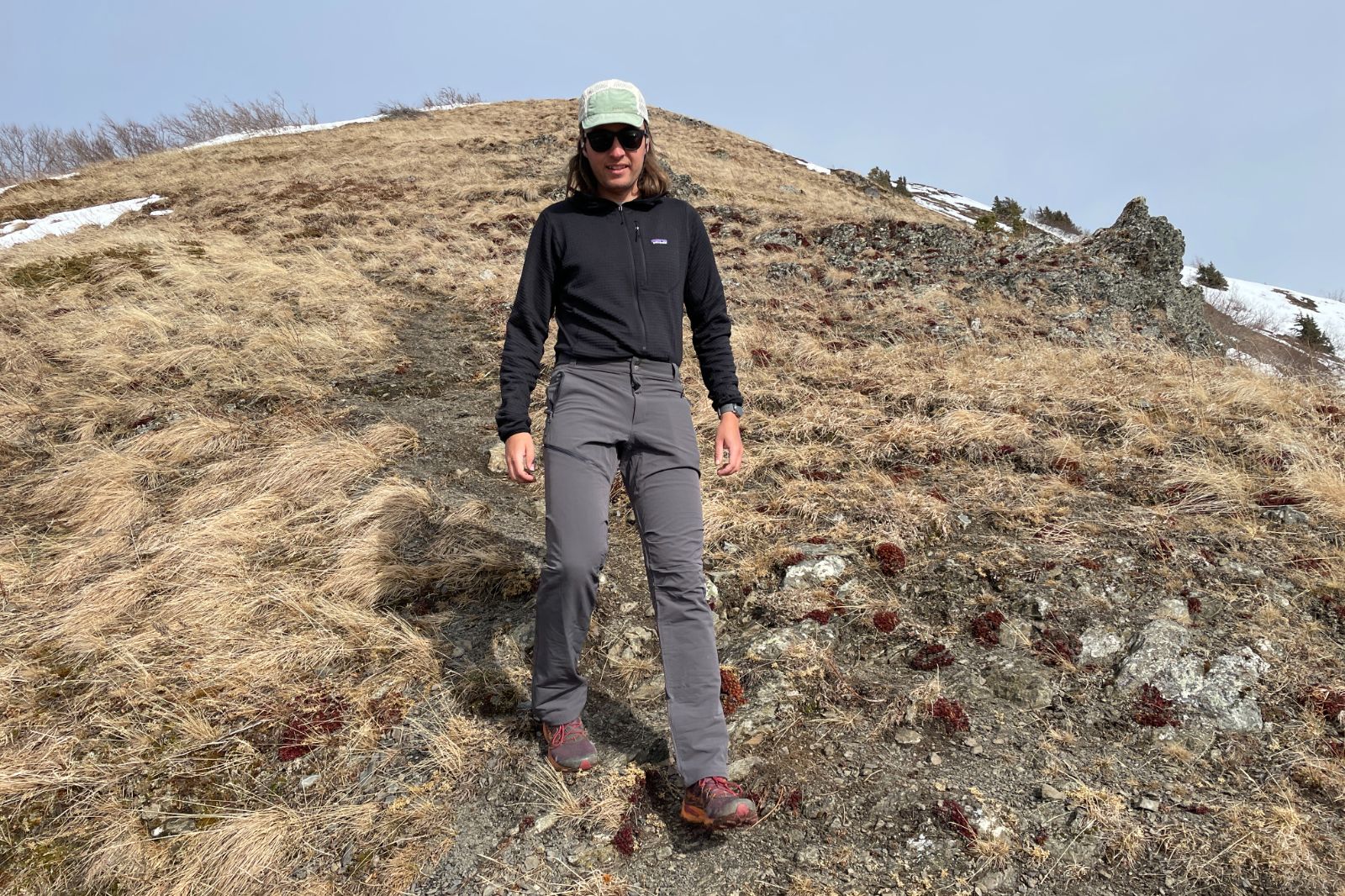 A man hikes downhill on a steep trail.