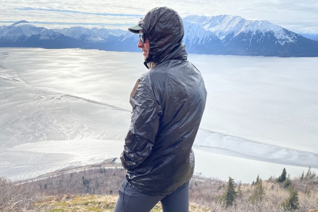 A man wears a windbreaker standing over a mountain view.