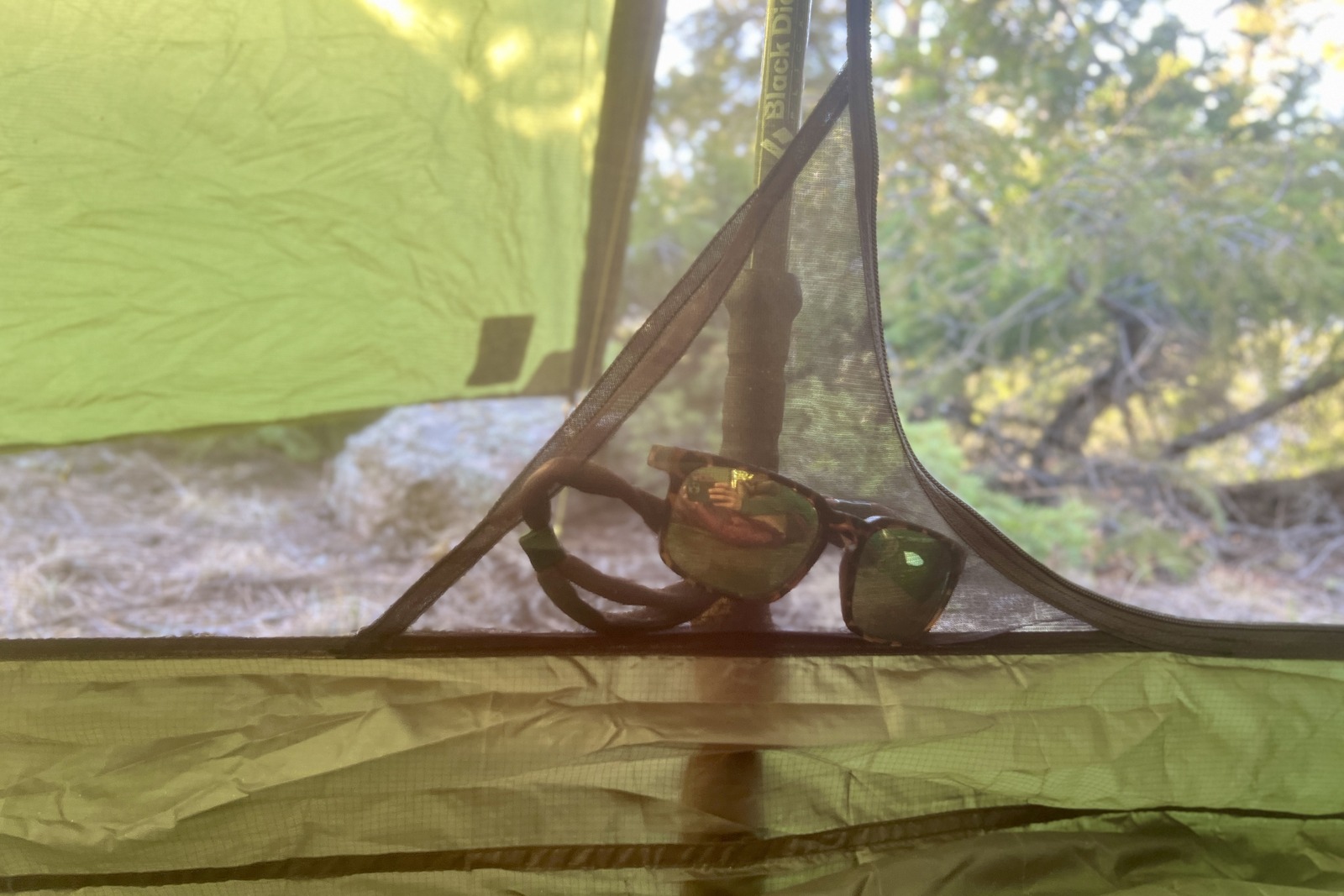 a close up of a pair of sunglasses in the small mesh pocket of a tent