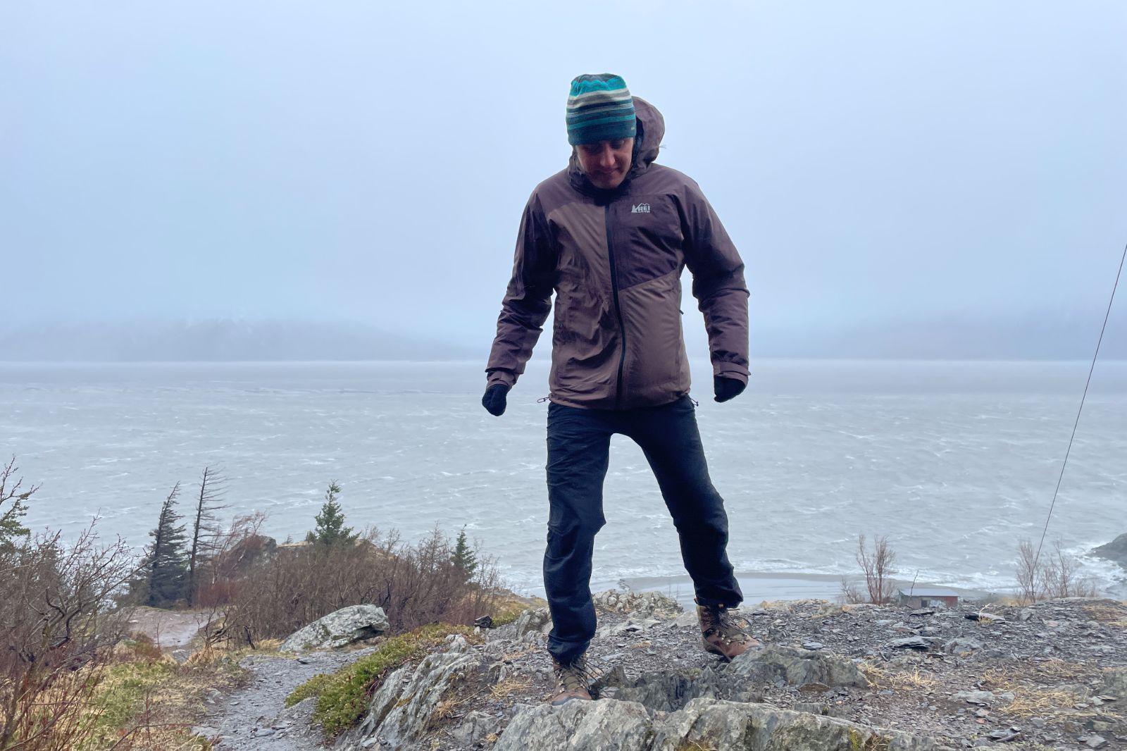 A man hikes in the rain above the ocean.