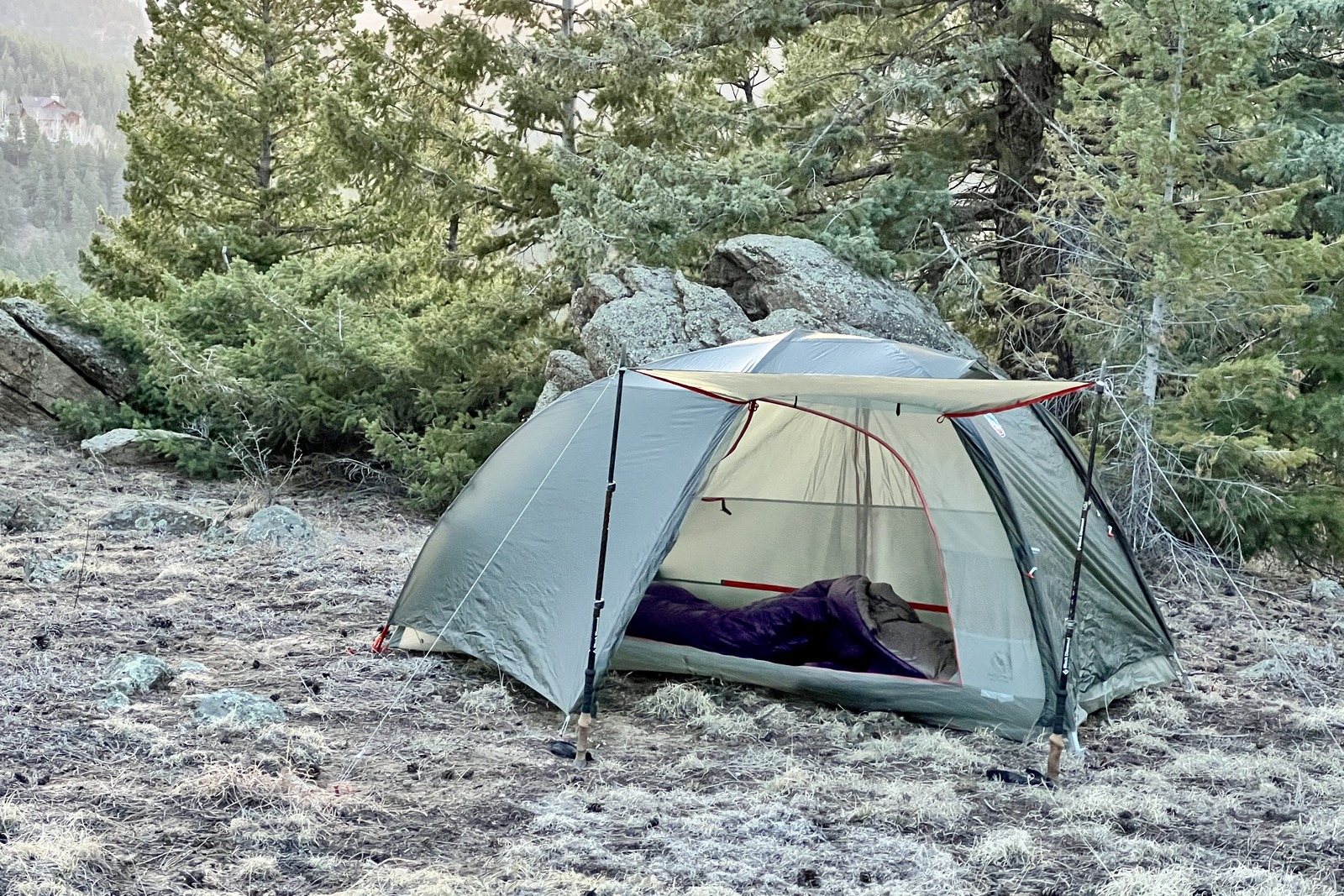 a tent is pitched in the forest with the awning deployed and the door open