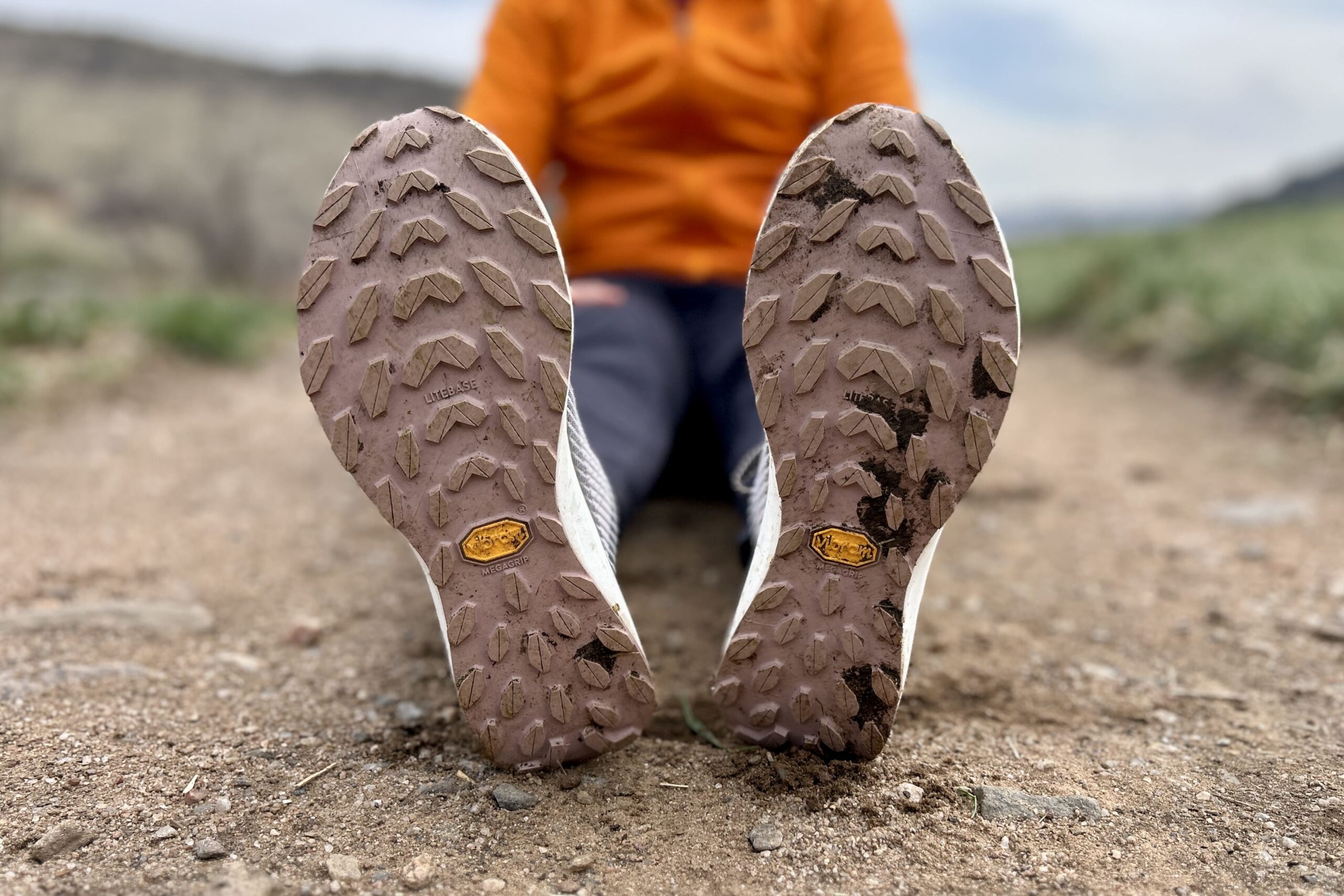 Close up of a pair of trail running shoes from the bottom, showing off the tread pattern.