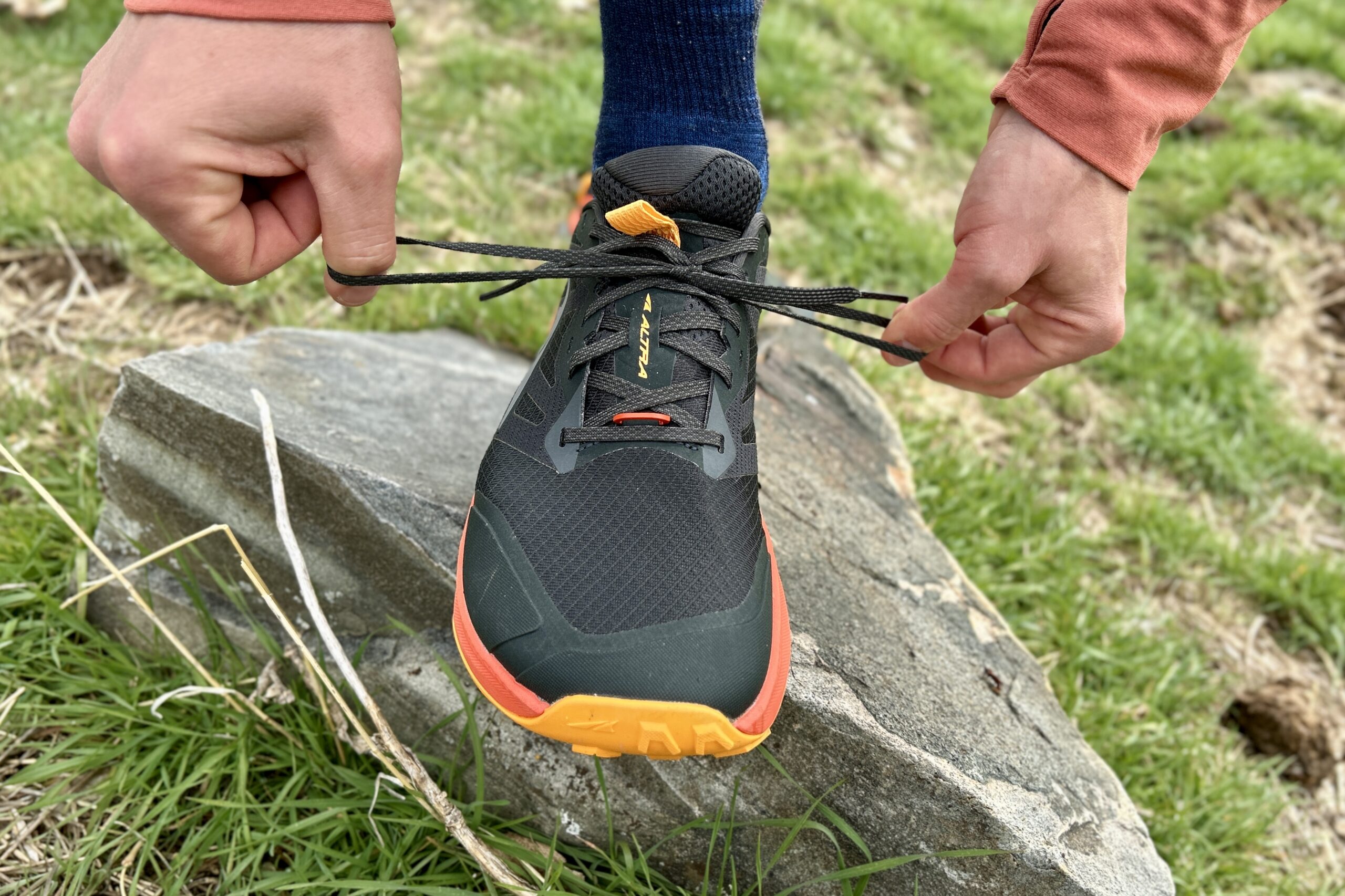 Close up image of a trail running shoe from the front as a person tightens the laces.