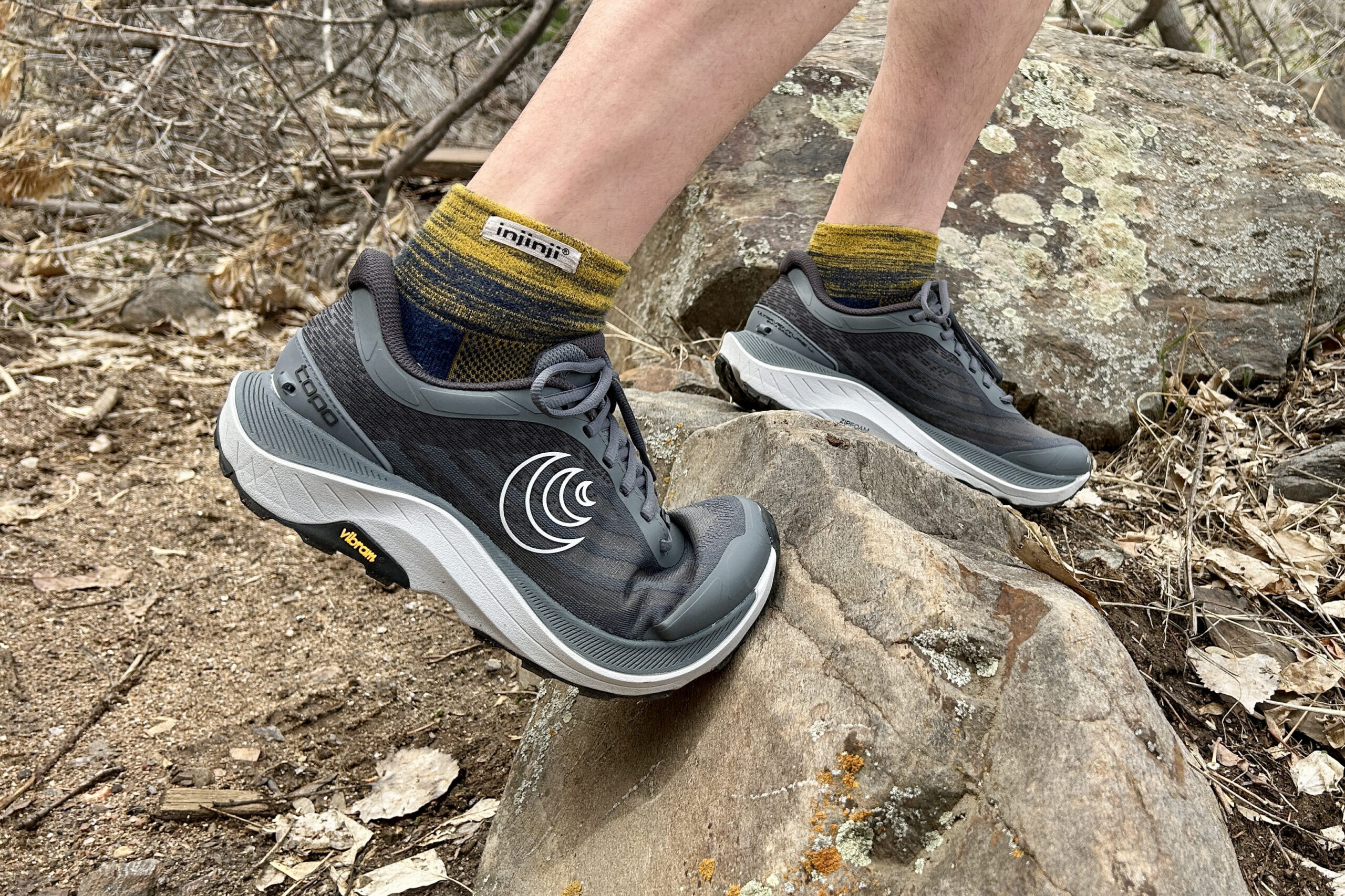 Close up image of a person walking over a rock in trail running shoes.