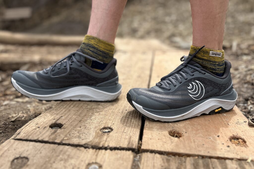 Close up from the knees down of a person wearing trail runners.