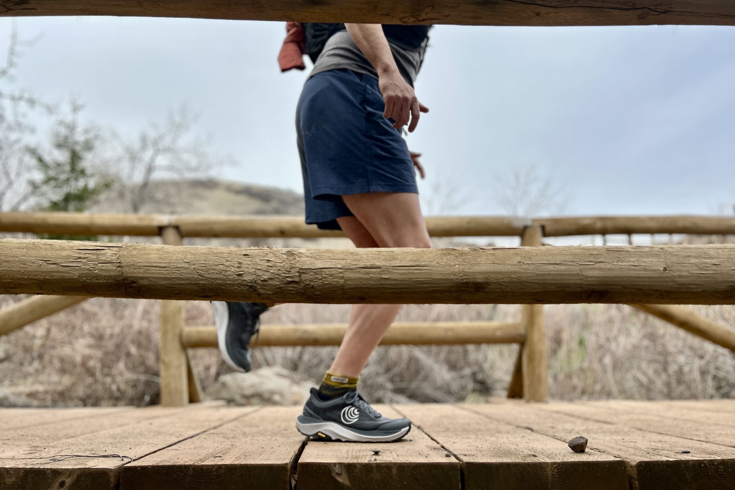 A person from the waist down running across a wooden foot bridge.