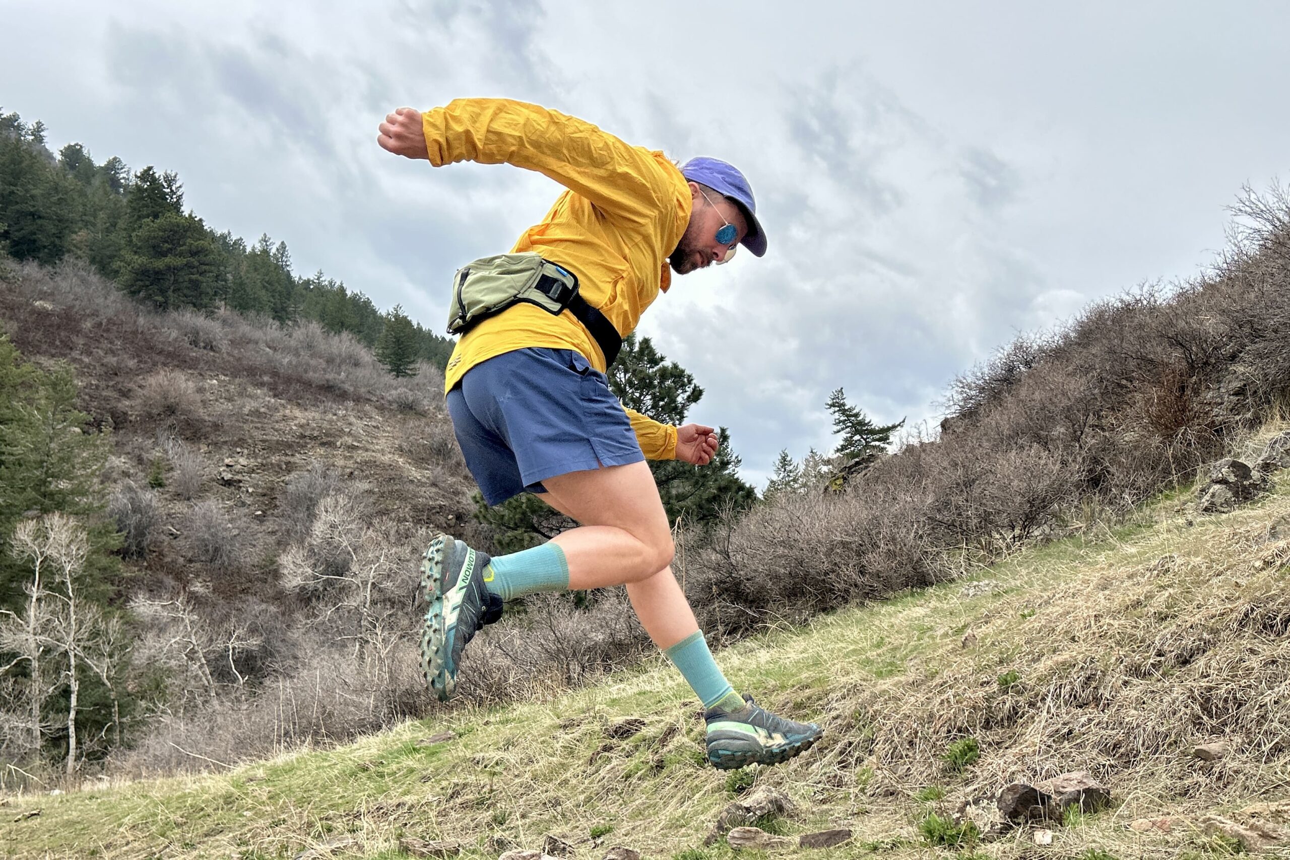 A man jumps in the air, with his legs and arms kicked out wearing running attire.
