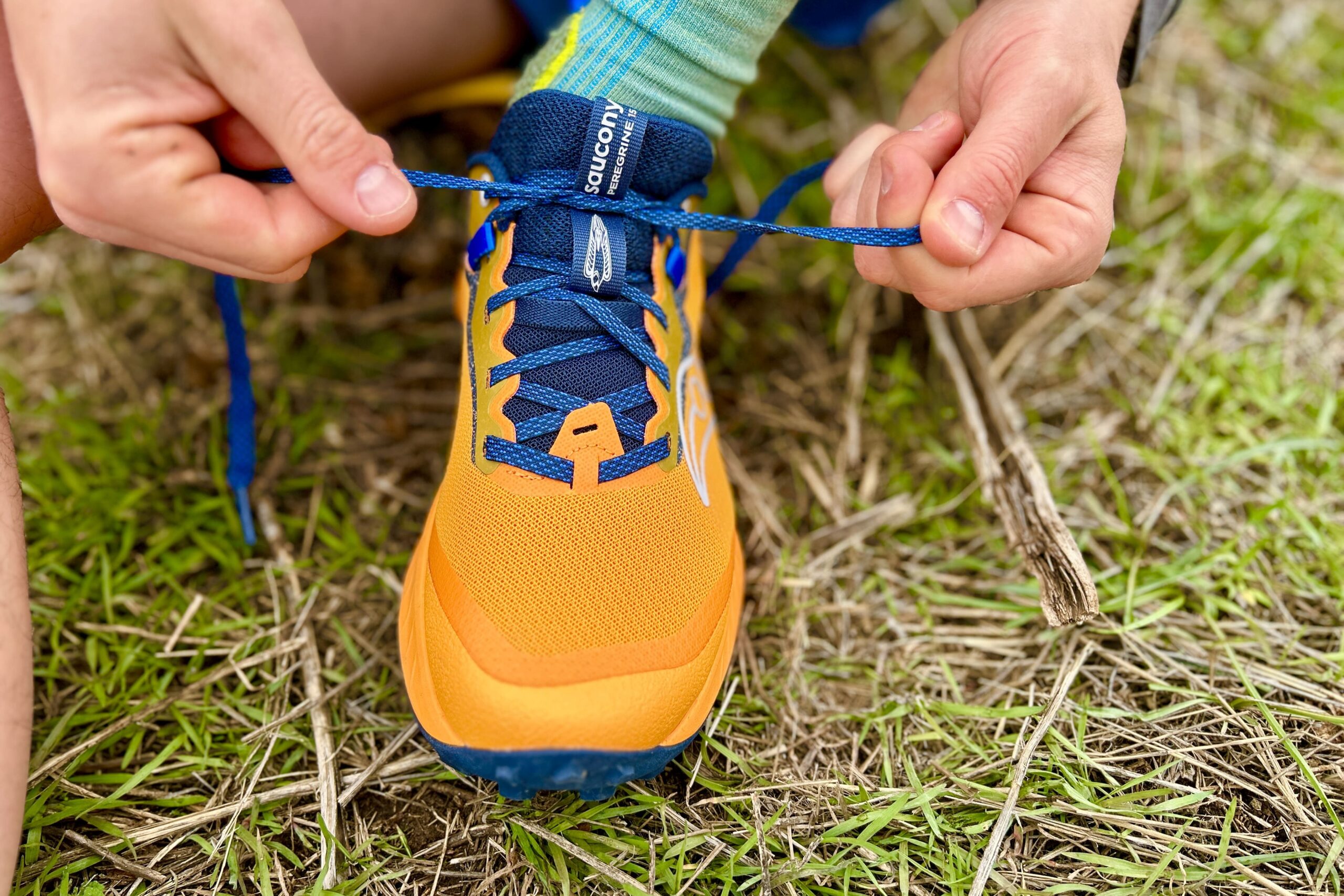 Close up image of a pair of hands tying the laces of a trail runner.