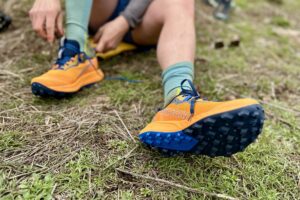 Close up image of a person sitting on a patch of grass tying their shoes