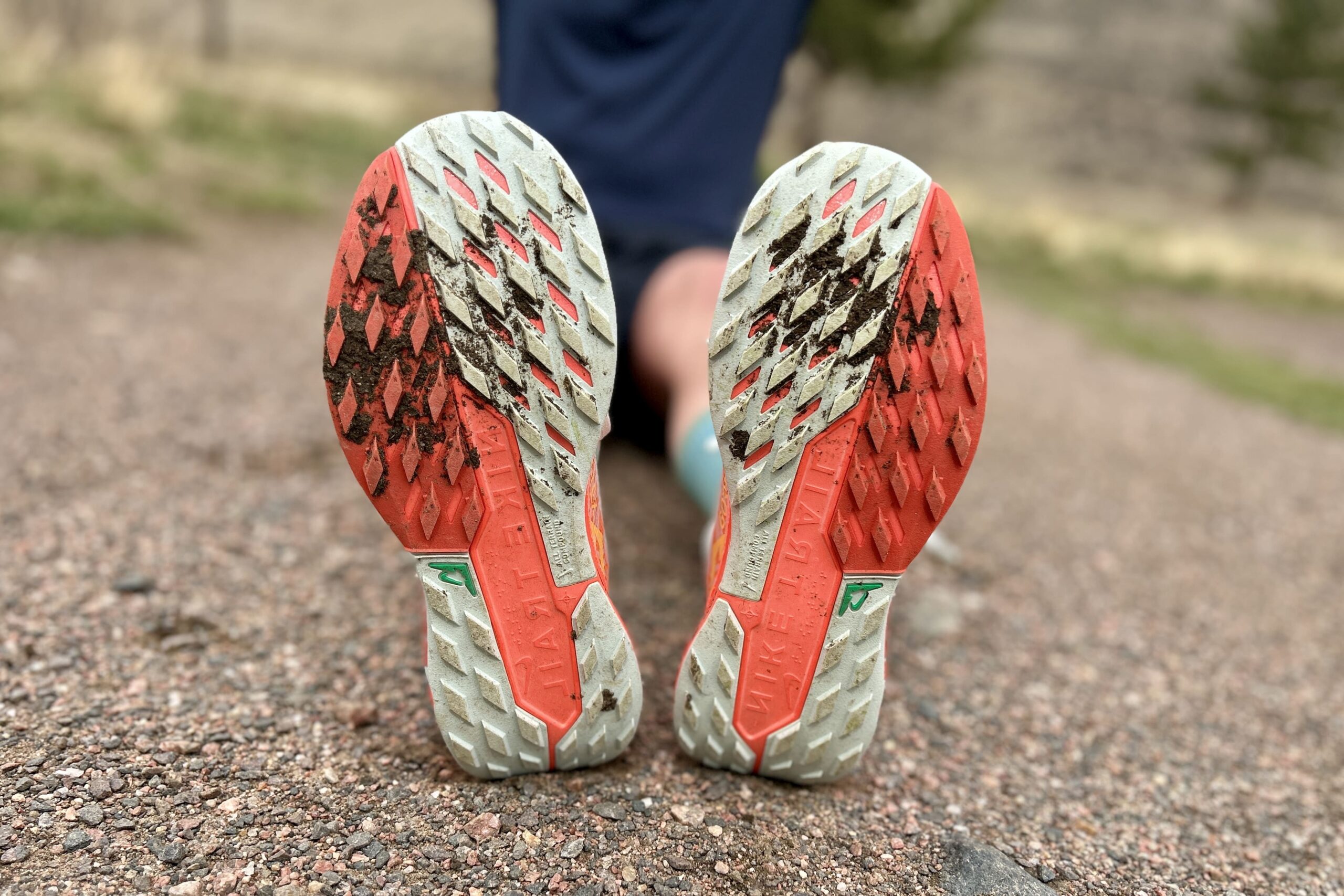 Close up of a pair of trail running shoes from the bottom, showing off the tread pattern.