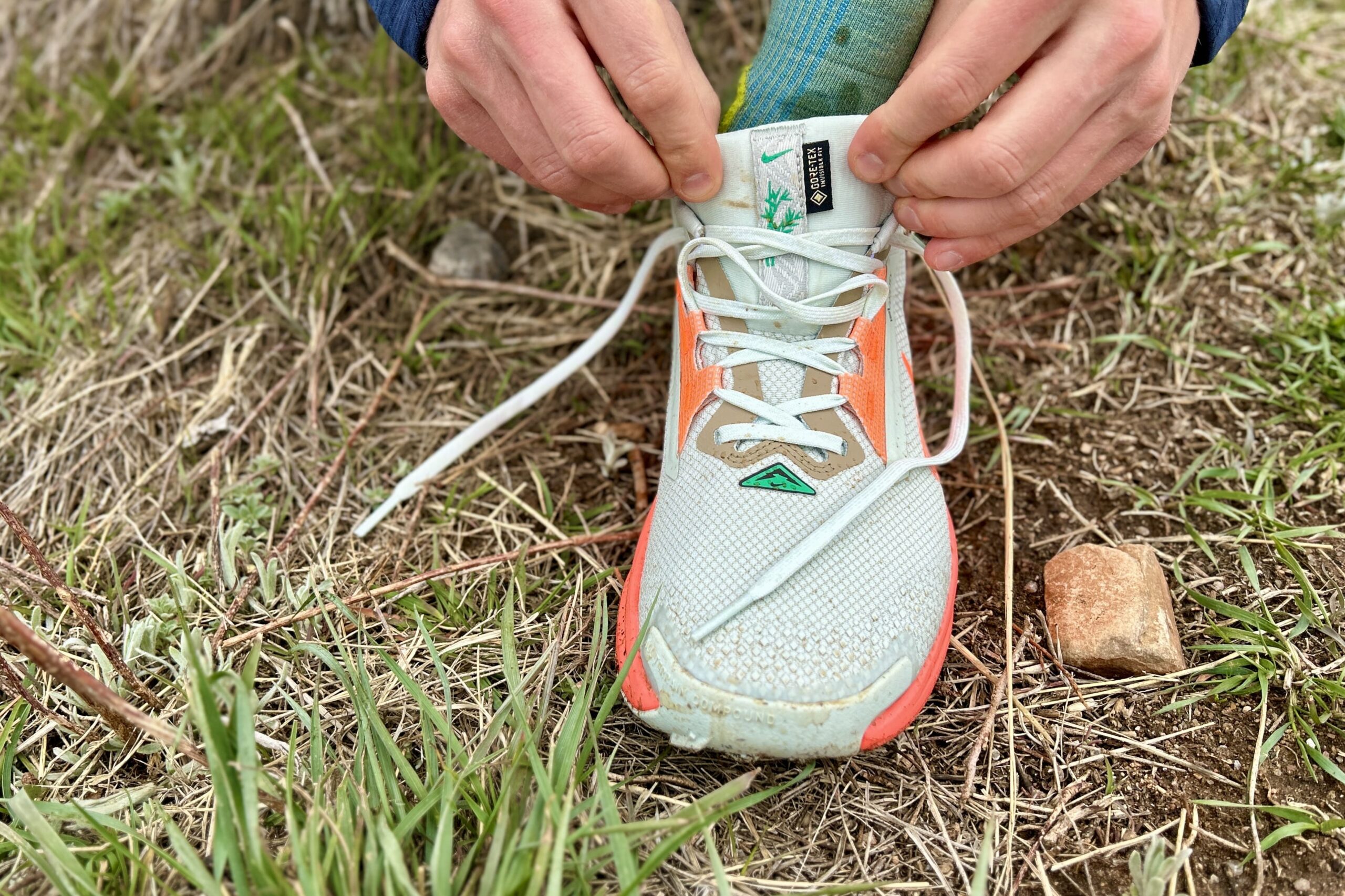 Close up image of a trail running shoe from the top as a person ties the laces.