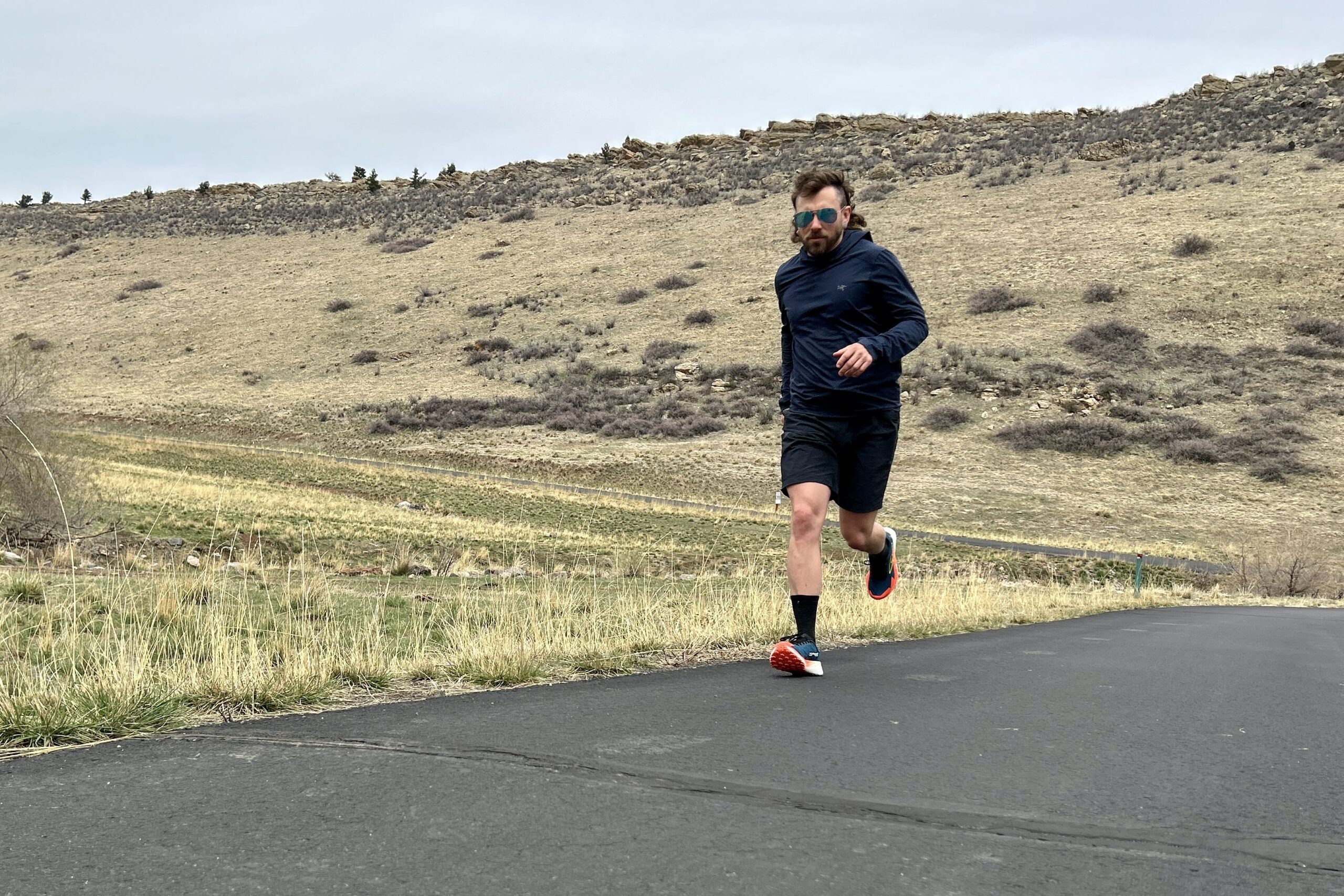 A man runs along a road in a mountain setting.