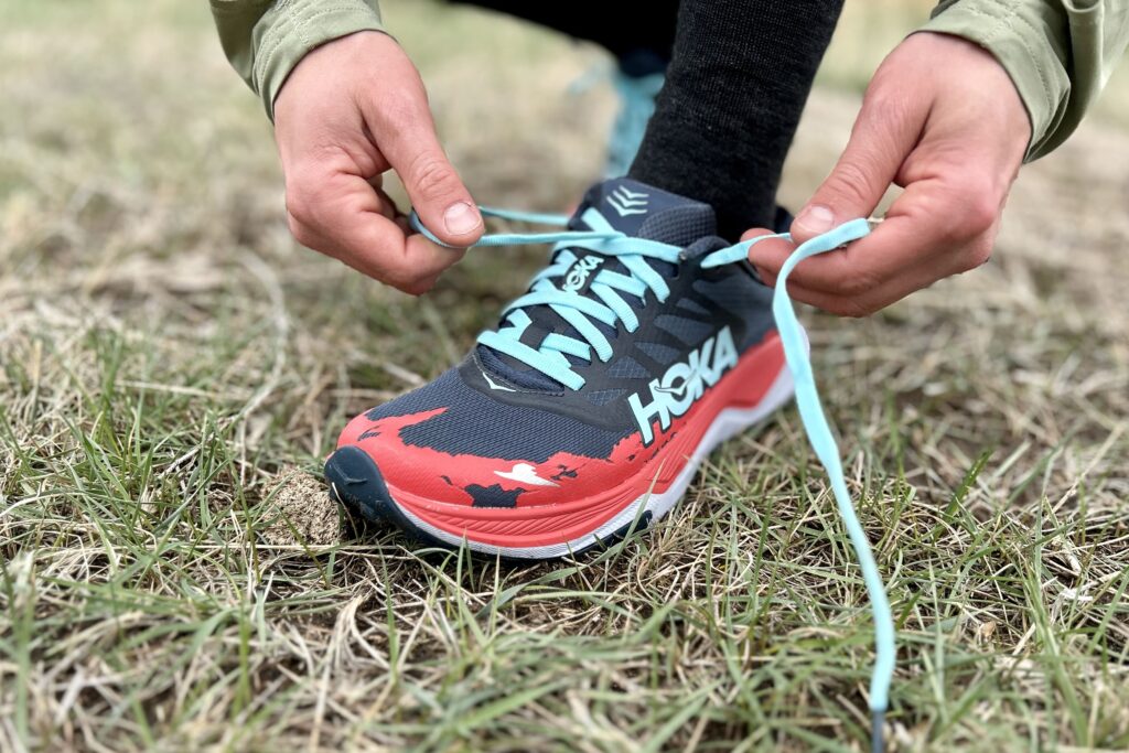 Close up image of a person tying a pair of trail running shoes.