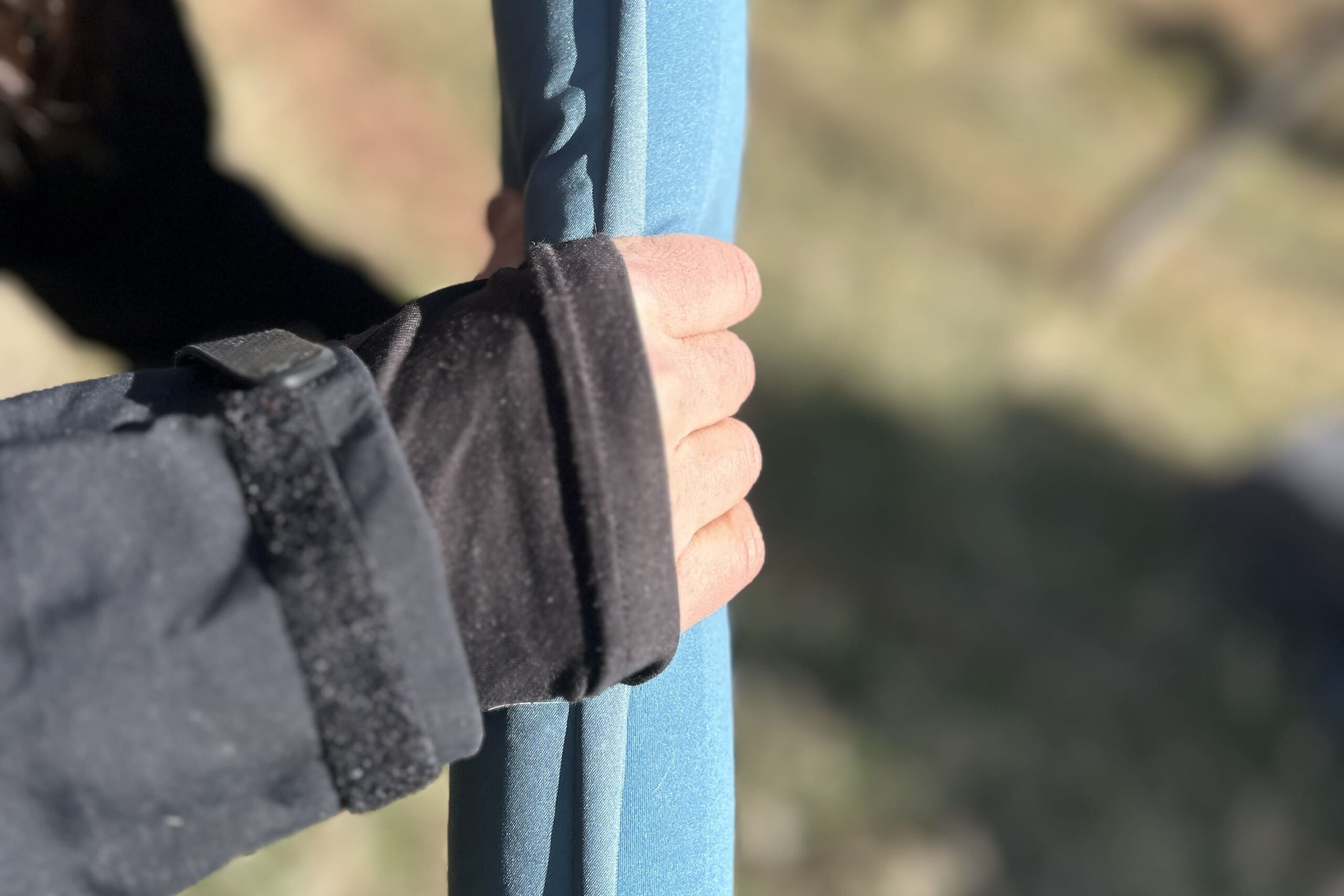 A person's hand holds the side of a thin sleeping mattress.