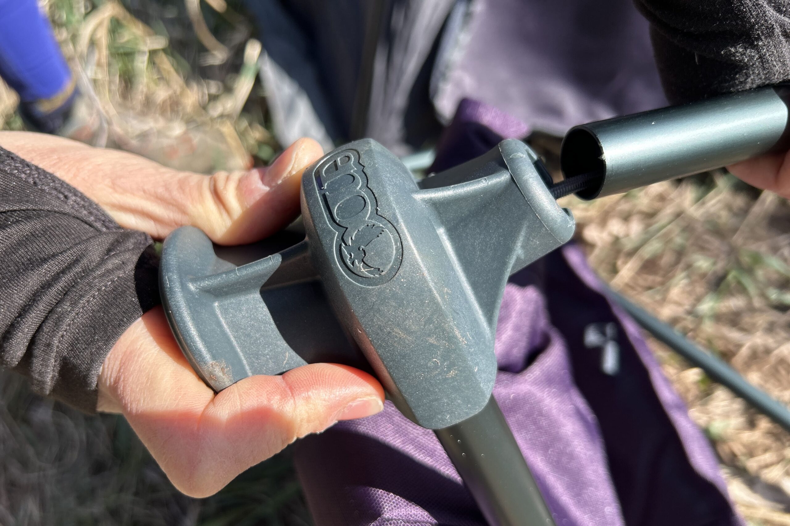 A person holds up a camping chair frame's connection hub.