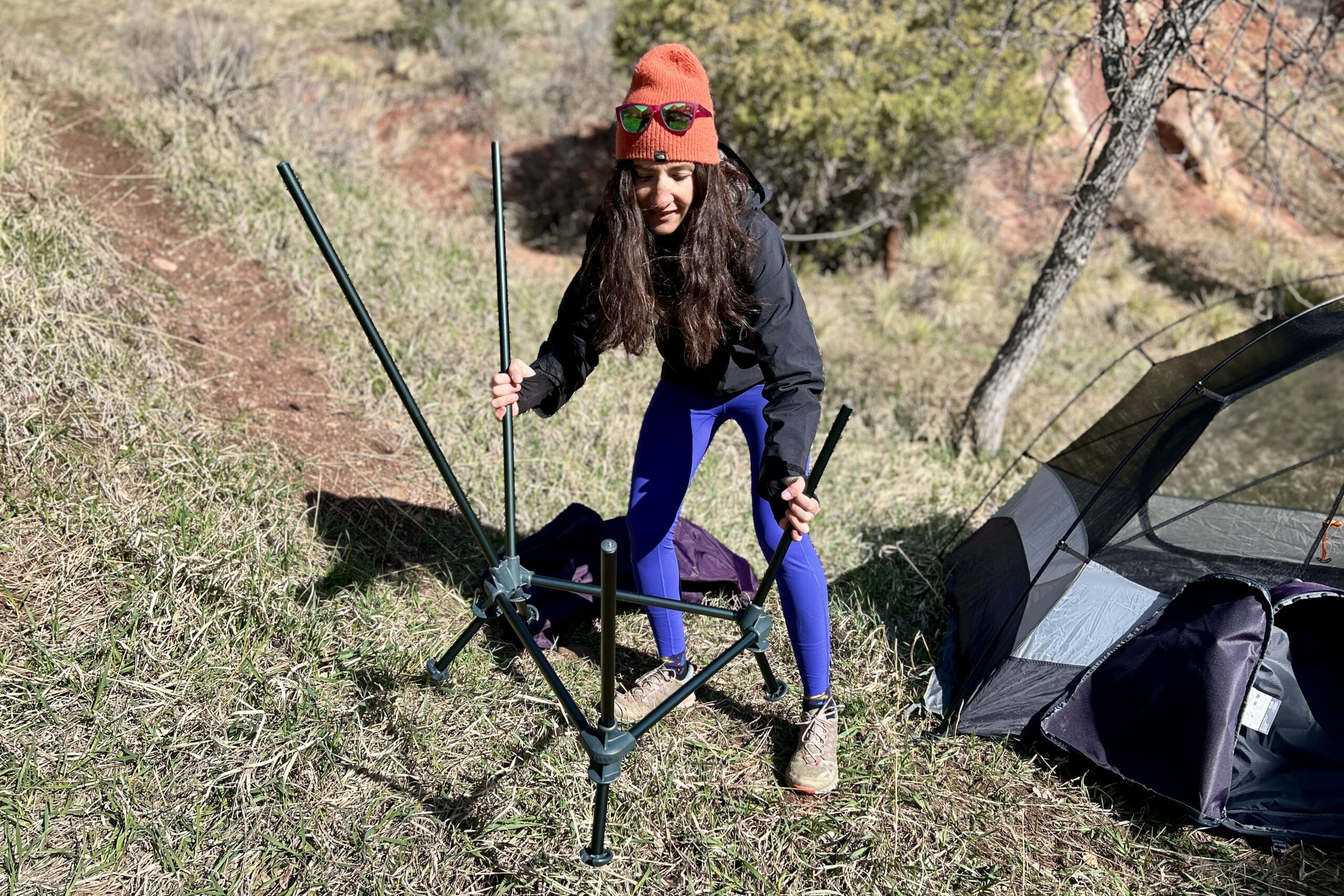 A woman sets the frame of a camping chair on the ground