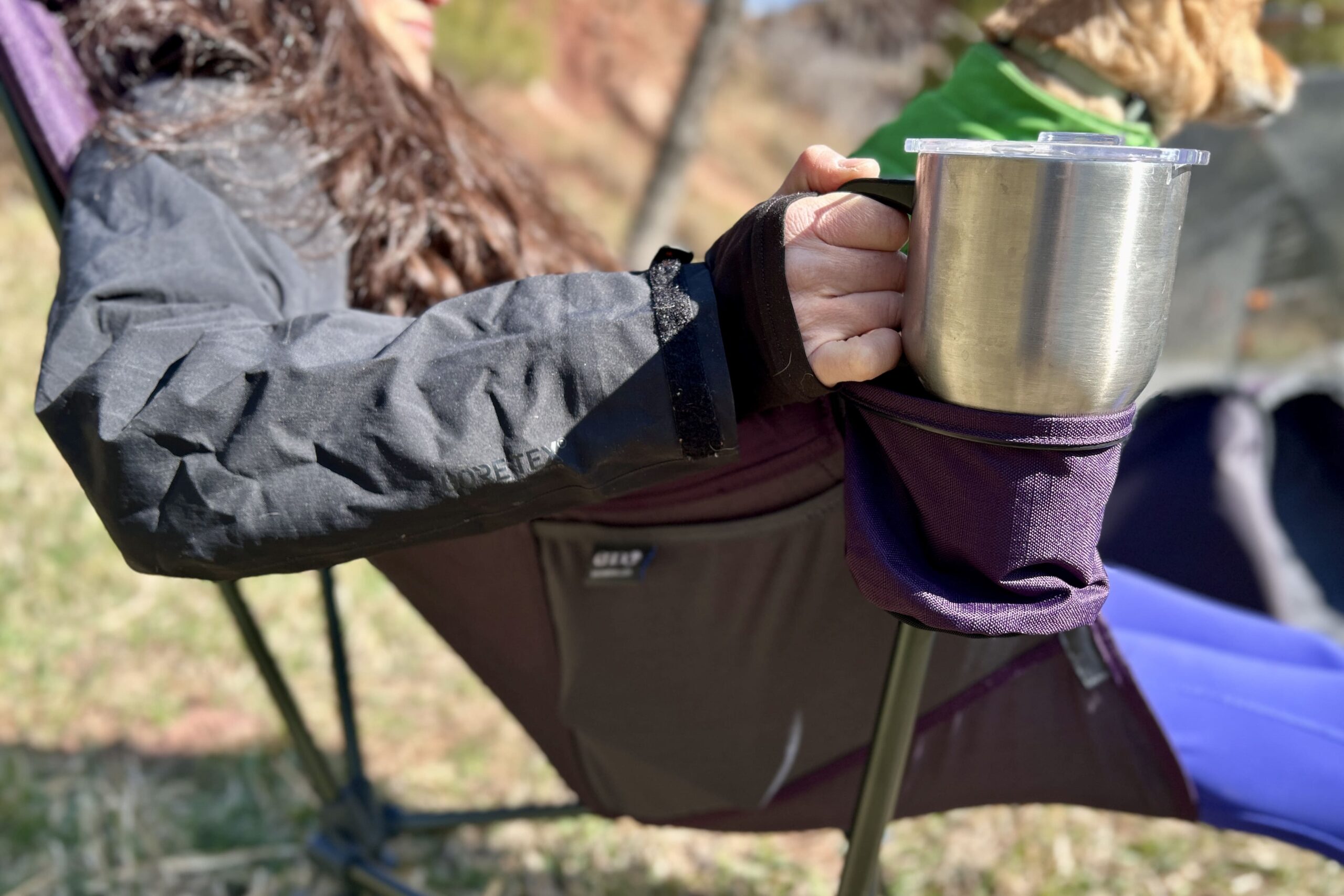 Close up image of a person with their hand on a coffee mug sitting in a cupholder.