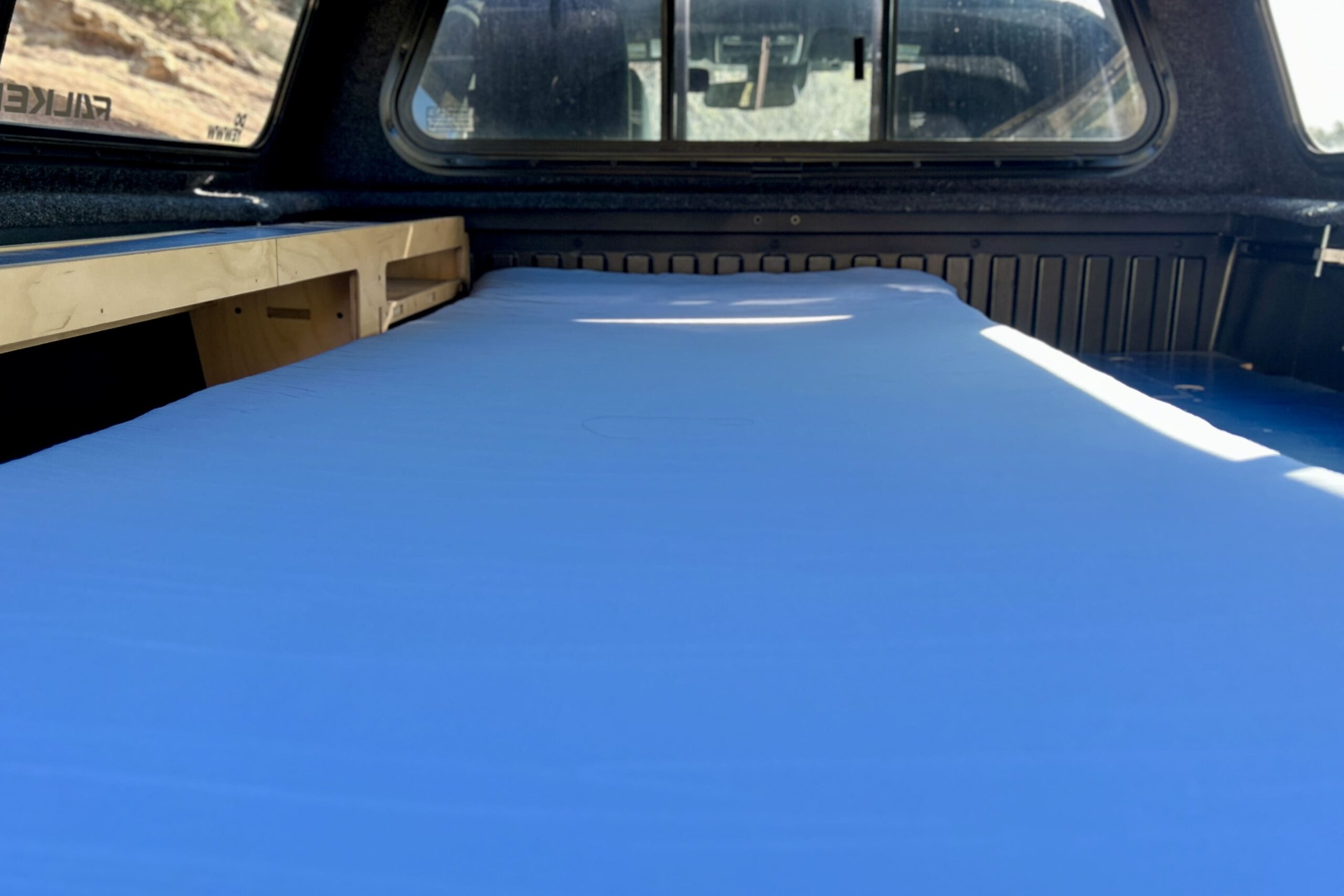 A camping mattress in the back of a pickup truck.